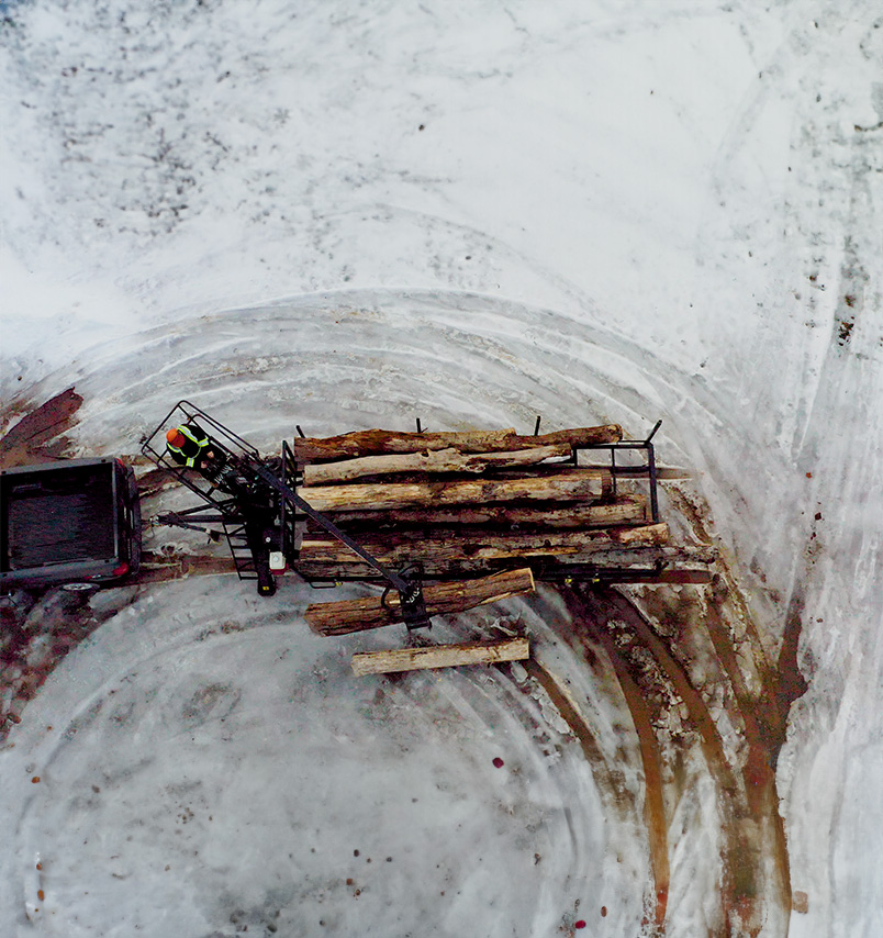 Black Horse Road Forestry Trailer Drone Log Loader Aerial view looking straight down at black horse road forestry trailer being unloaded by log loader